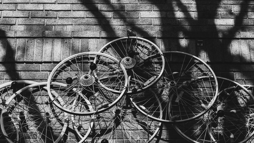A striking black and white abstract photograph of multiple bicycle wheels against a brick wall in Somerville, Massachusetts.