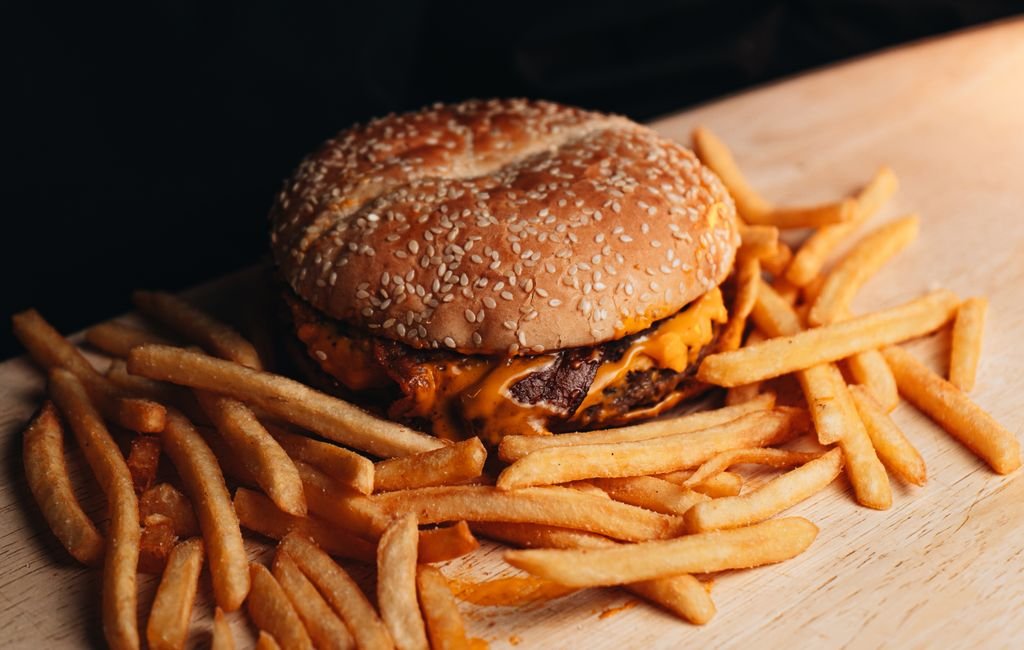 Delicious cheeseburger with fries on a wooden table, perfect for food lovers.