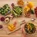 Top view of fresh vegetables and salad preparation on a wooden table, perfect for healthy eating concepts.