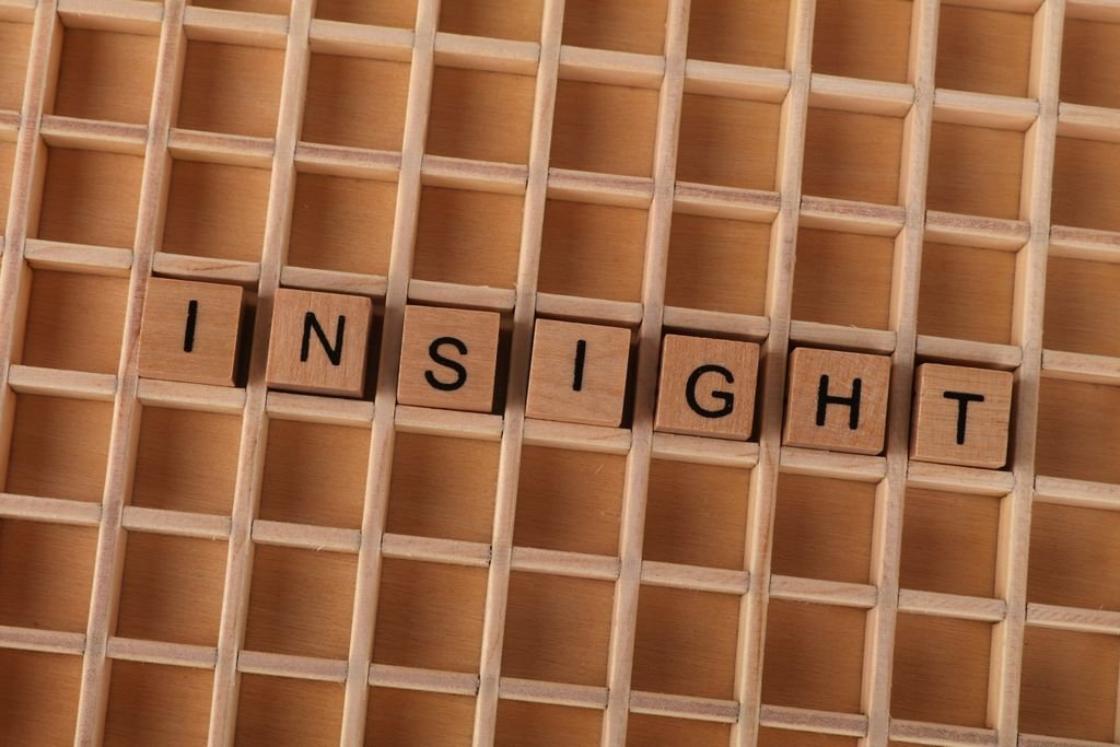 Wooden Scrabble letters spelling 'INSIGHT' on a wooden grid creating a conceptual image.