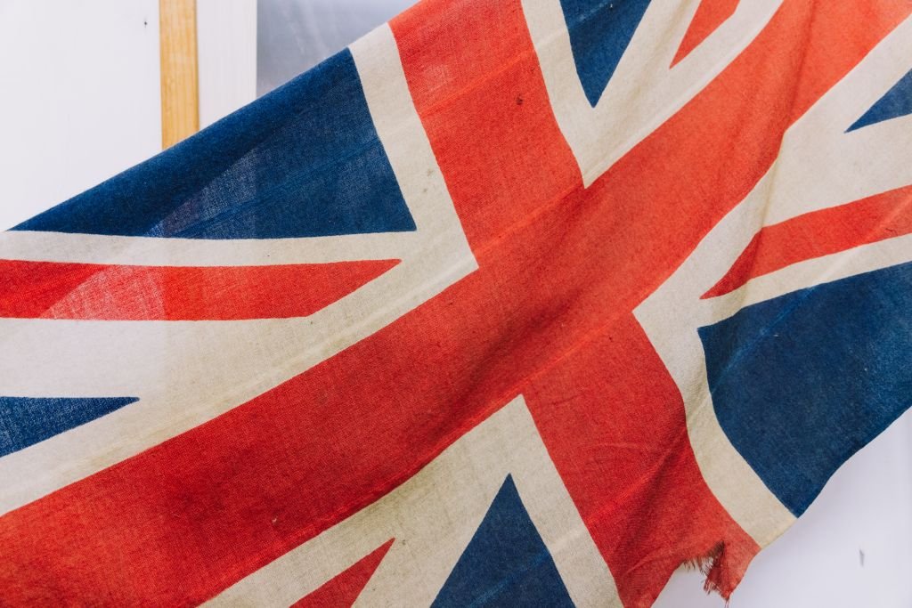 A detailed close-up of a weathered Union Jack flag, displaying its distinct colors and texture.