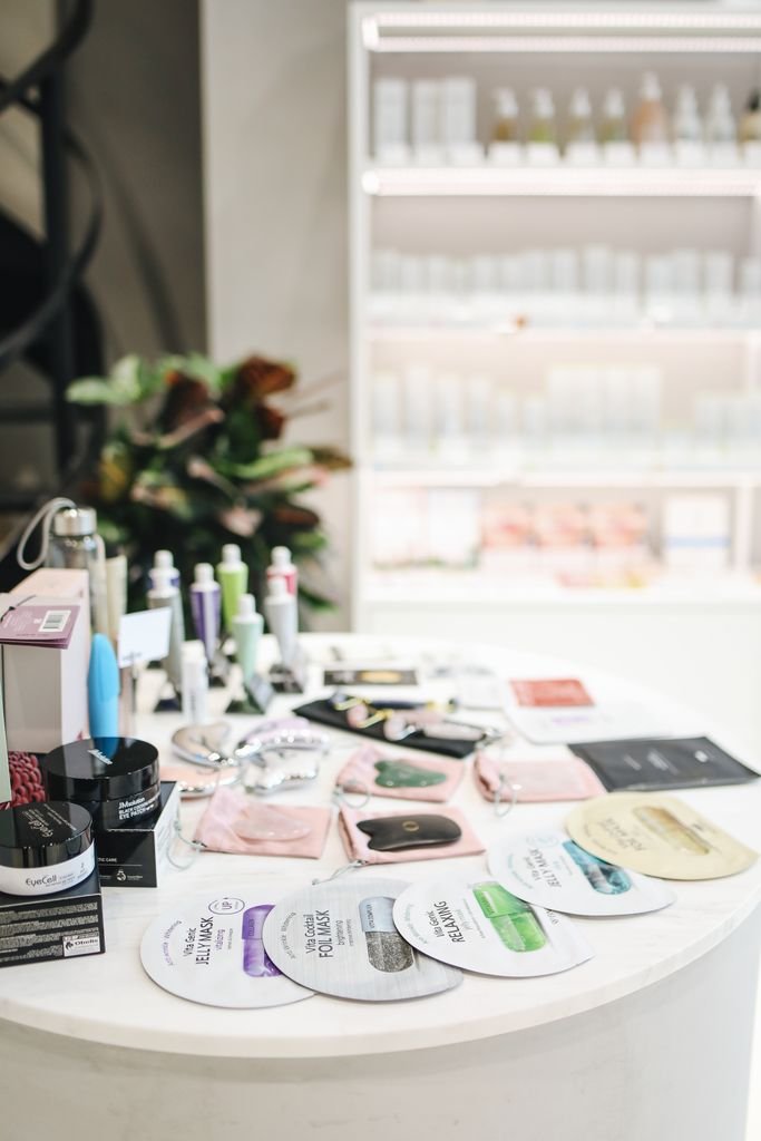 A diverse collection of skin care products neatly arranged on a white counter inside a modern store.