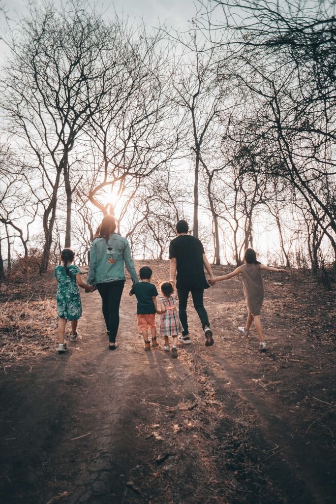 A family holding hands and walking along a bare path during a winter day, emphasizing unity and togetherness.