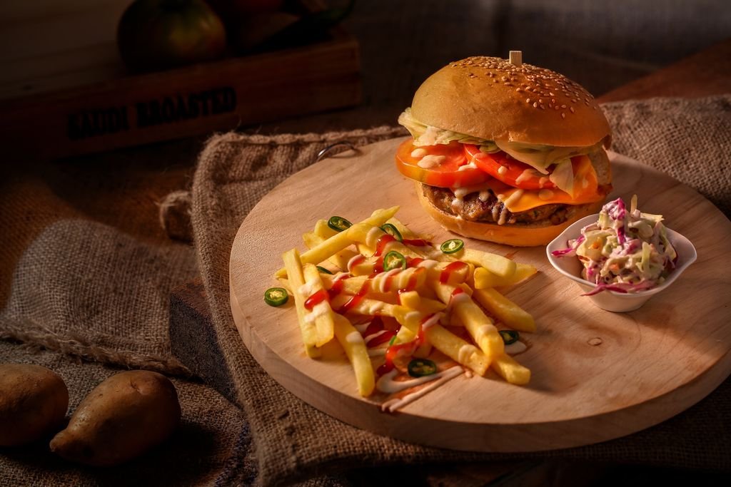 A mouthwatering cheeseburger with fresh fries and coleslaw on a rustic wooden board. food