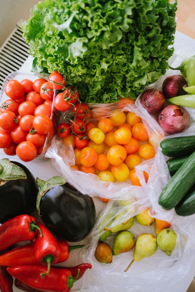 A vibrant assortment of fresh vegetables including tomatoes, peppers, cucumbers, and lettuce displayed on a table. food