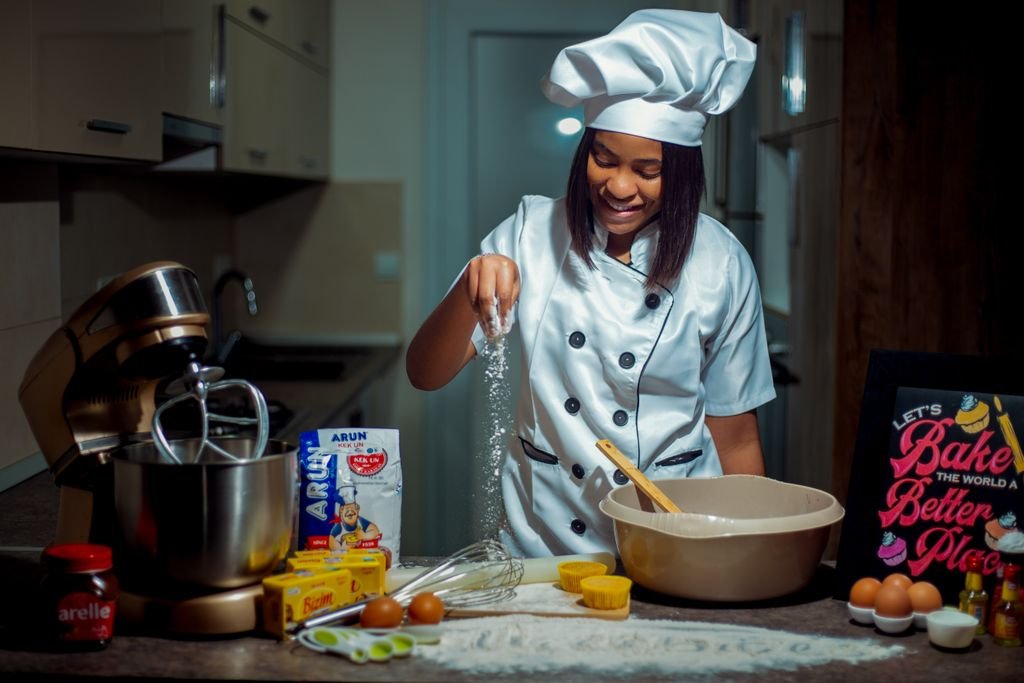 A young chef in a modern kitchen preparing dough with various baking ingredients. food