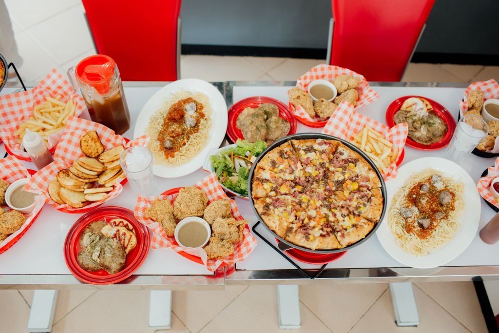 An inviting display of assorted fast food items featuring pizza, fried chicken, spaghetti, and french fries, ideal for a hearty meal.