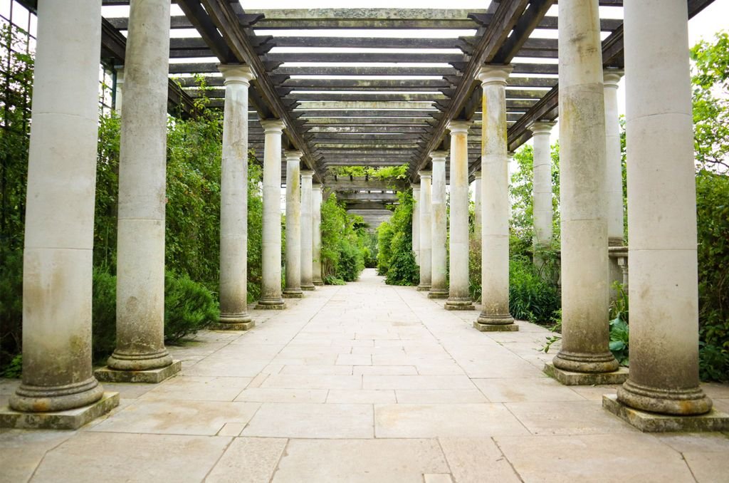 Beautiful stone pathway lined with classic columns and greenery, offering a serene outdoor escape.