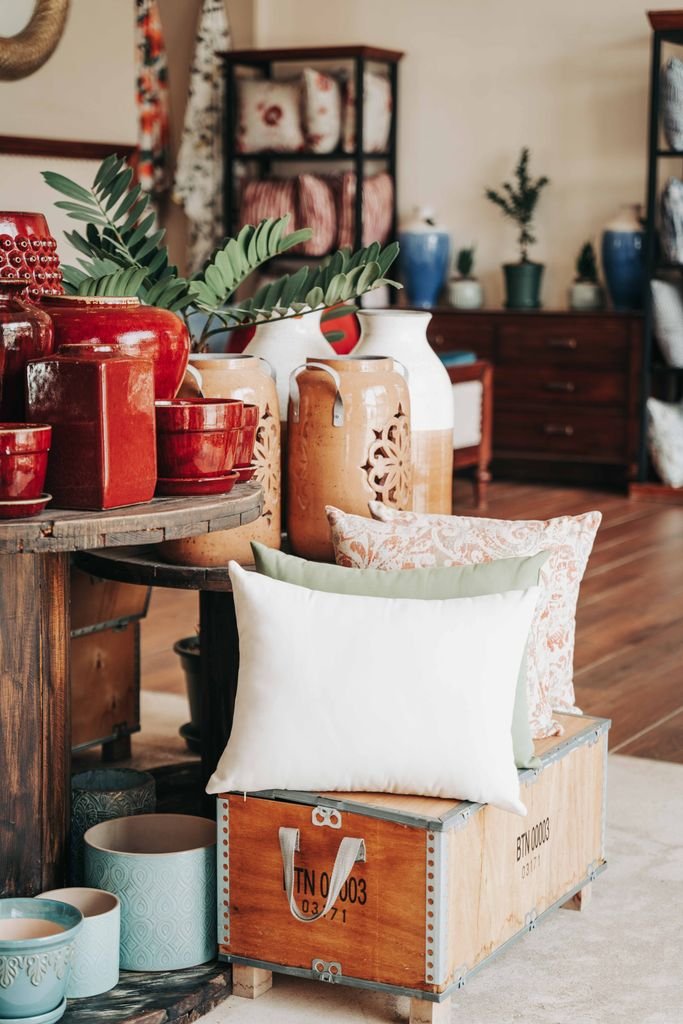 Charming home decor setup with pillows, jars, and plants for a cozy ambiance.