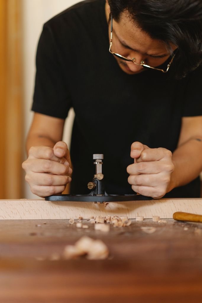 Crop concentrated male master in glasses processing wood with manual router plane in joinery workshop