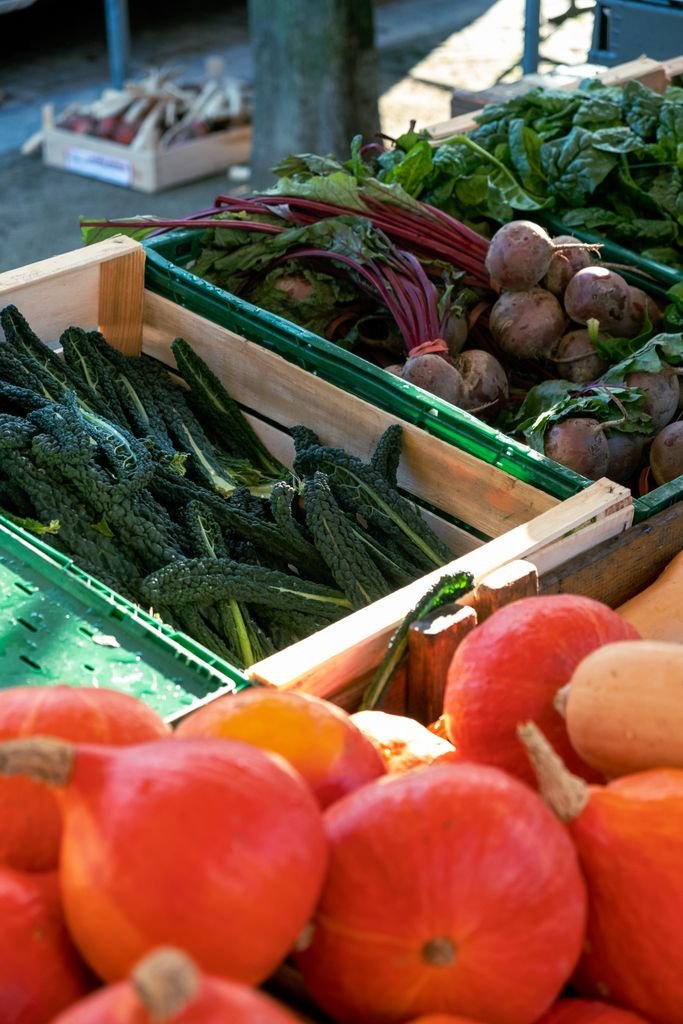 Fresh vegetables displayed at a bustling farmer's market stall, showcasing a colorful variety.