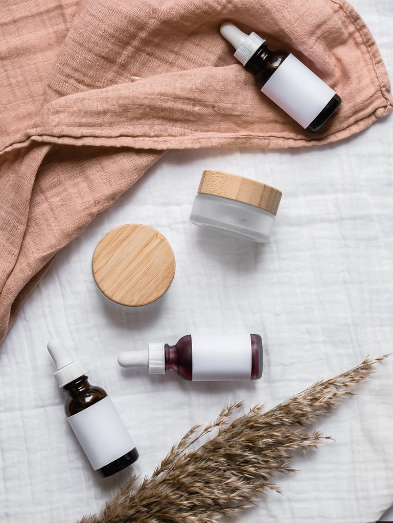 Stylish flat lay of serum bottles and jars on soft fabric with a natural, earthy aesthetic. skin