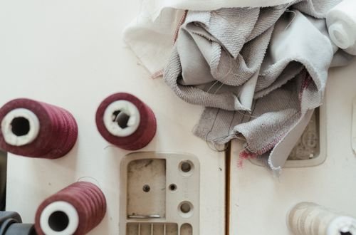 Flat lay of sewing materials including spools of thread and fabric on a workbench, ideal for crafting and textile themes.
