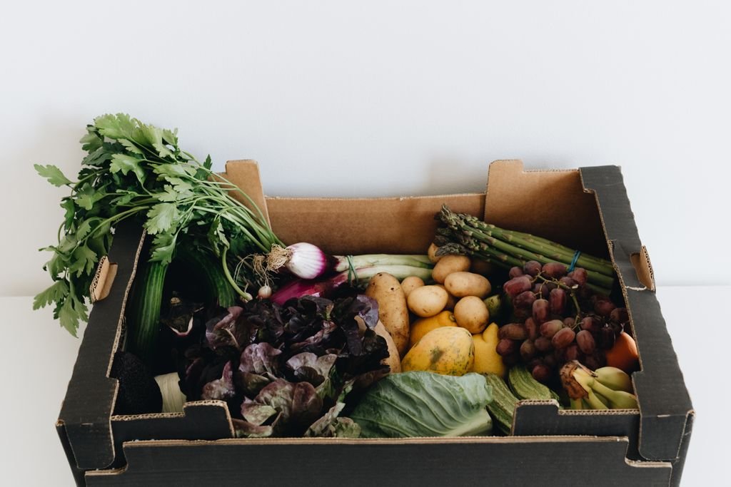 Healthy assortment of fresh vegetables and fruits packed in an eco-friendly cardboard box.