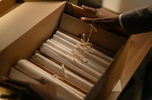 Hands organizing files in a box, symbolizing investigation and research.